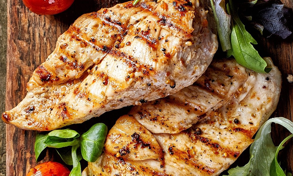 Grilled chicken breast with fresh greens and tomatoes.