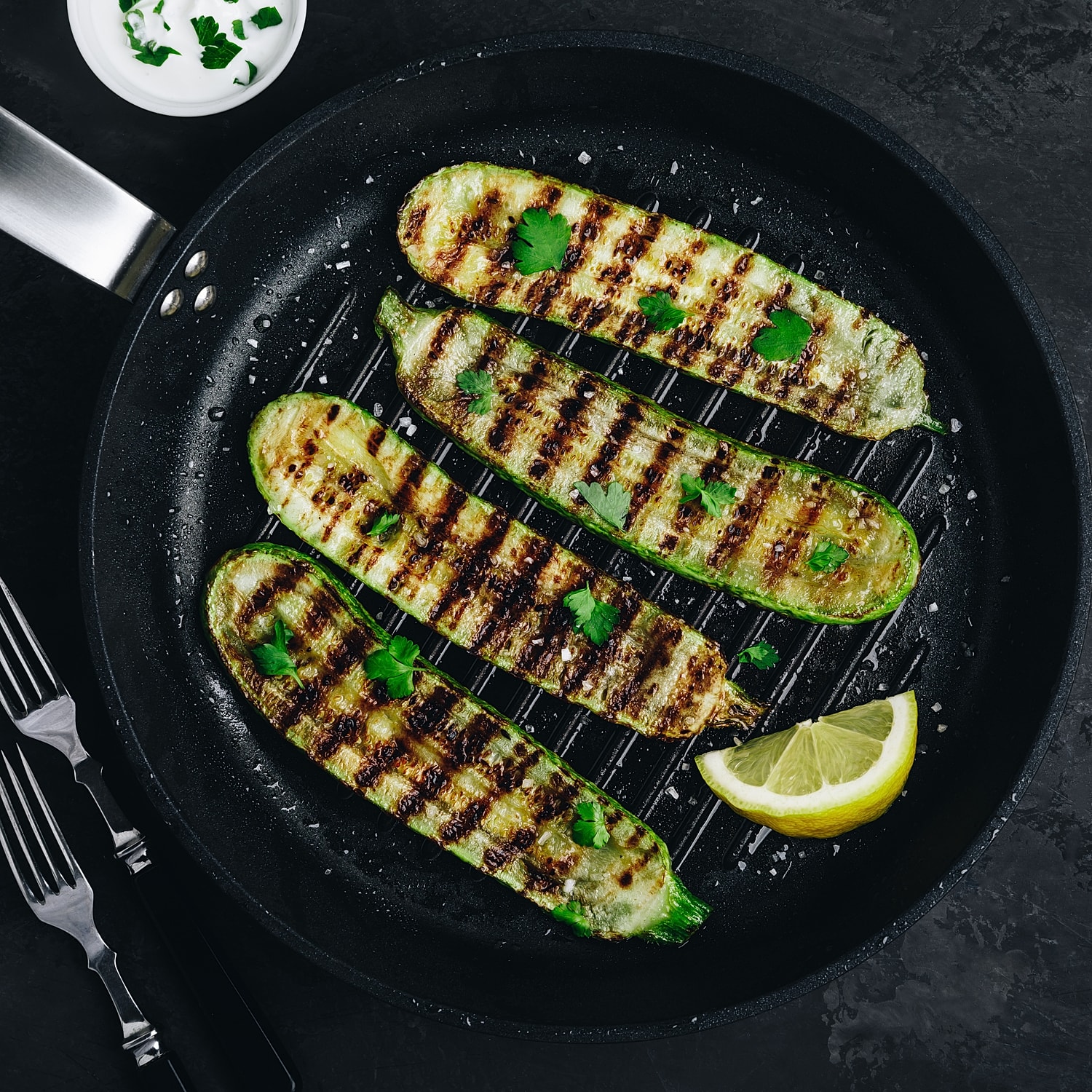 Grilled zucchini garnished with herbs and lemon.