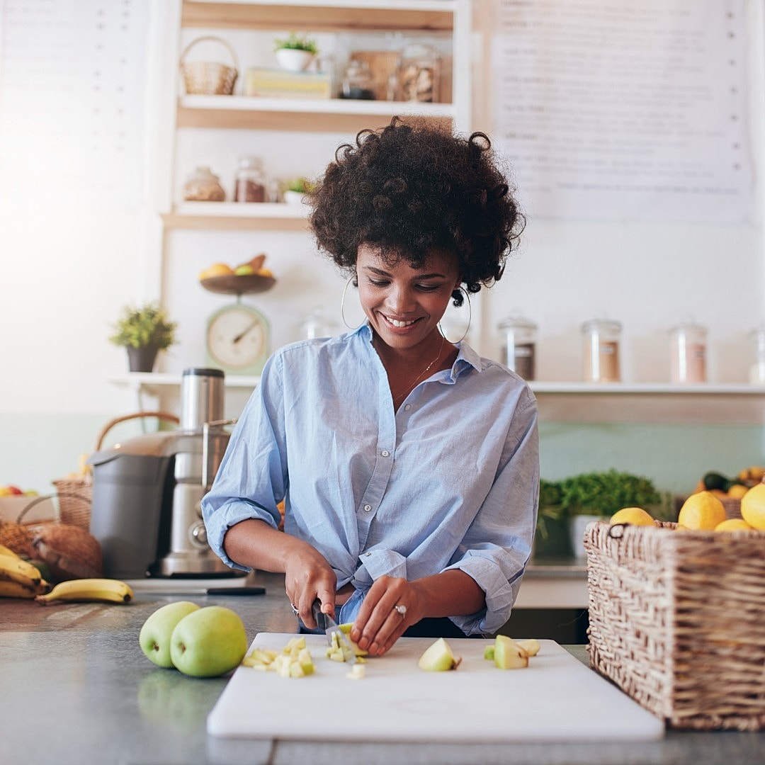 Woman chopping apples in a bright kitchen.