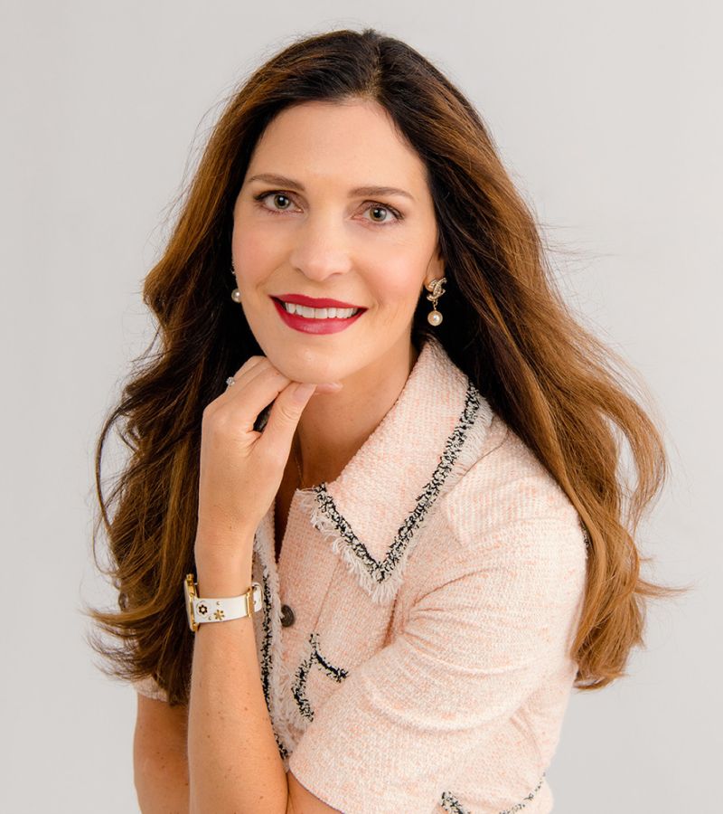 Woman with long hair and red lipstick smiling.