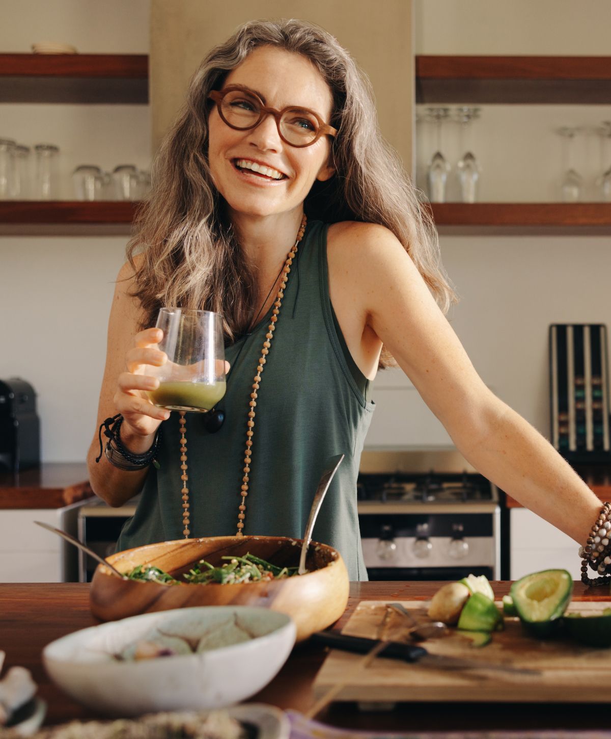Woman enjoying a drink in a kitchen setting.