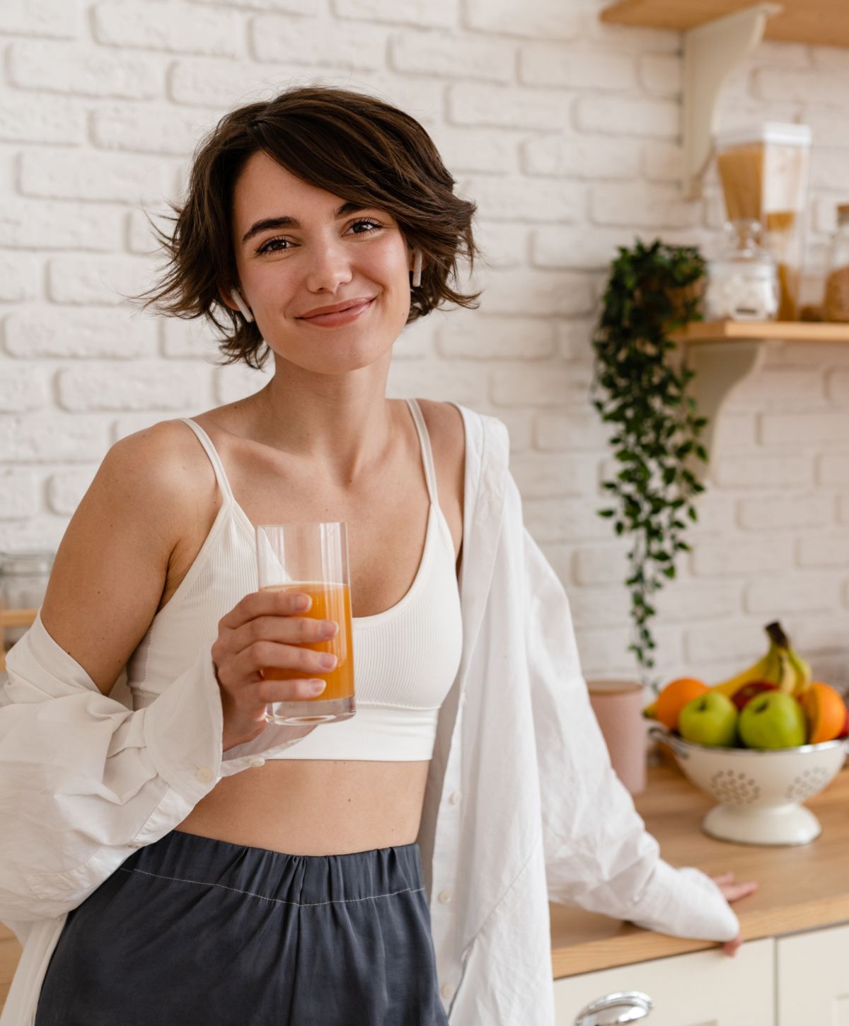 Woman enjoying juice in a bright kitchen.