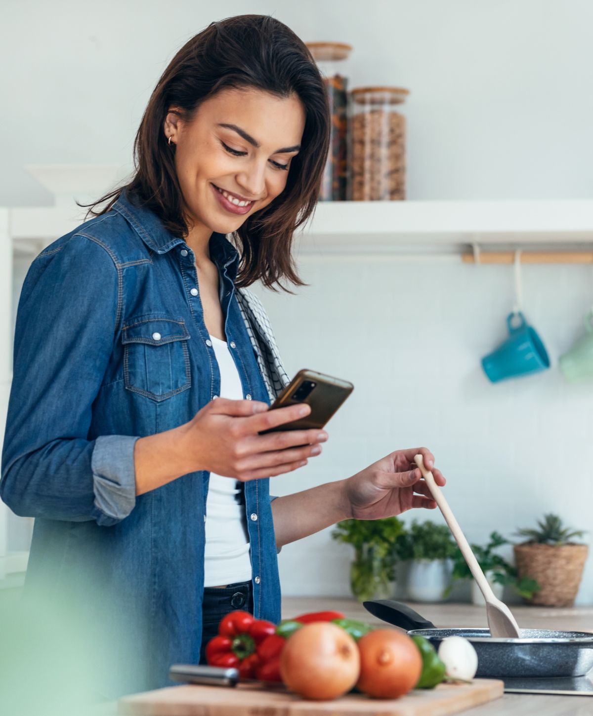 Woman blending ingredients while using her phone.