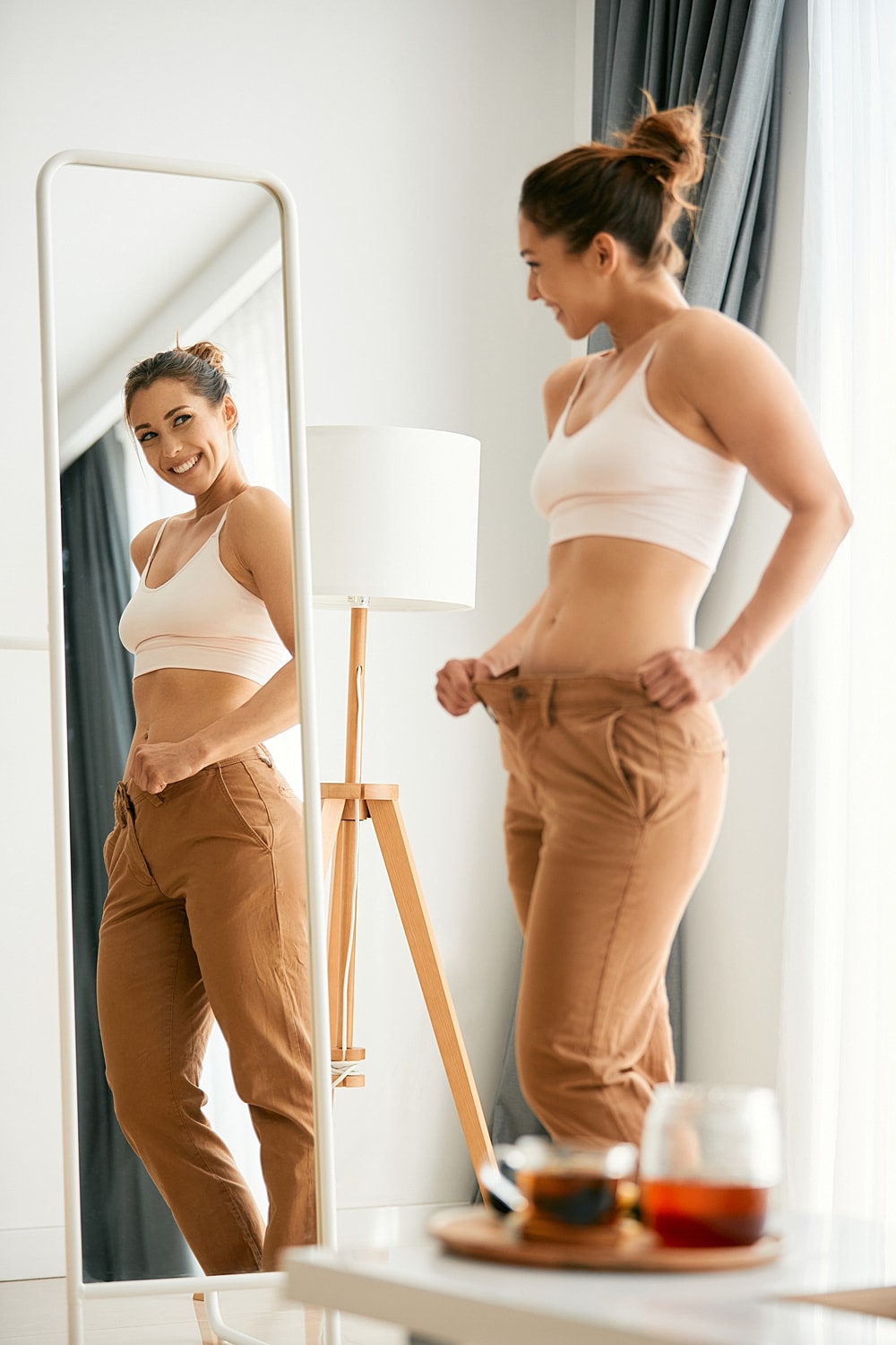 Woman smiling in mirror, trying on clothes.