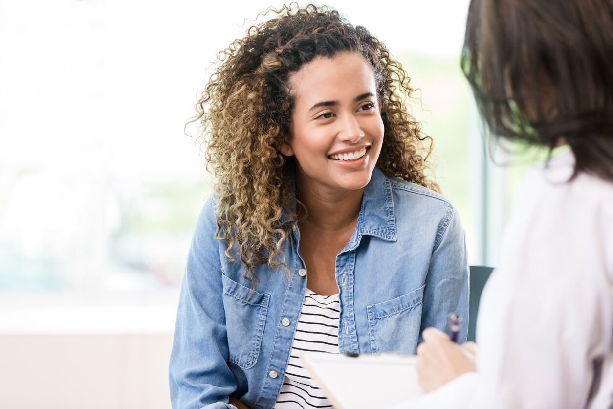 Smiling woman talking with another person indoors.