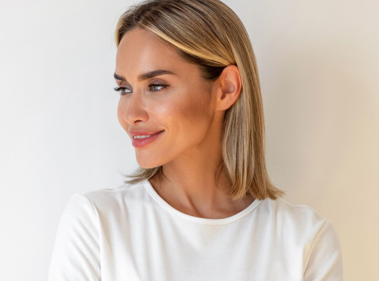 Smiling woman in white shirt against light background.