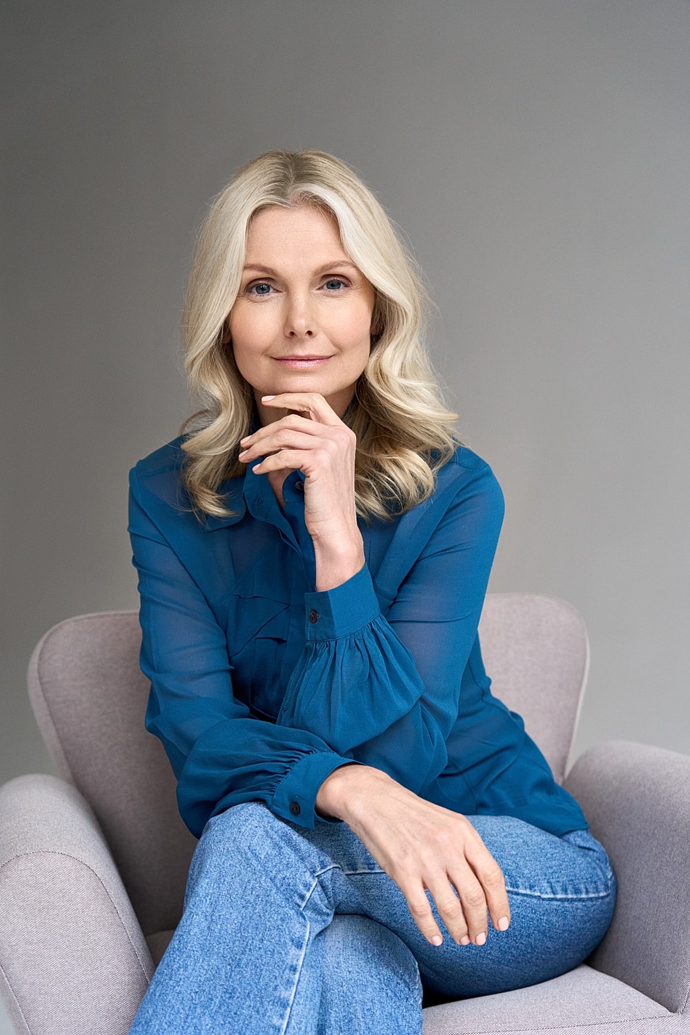 Woman in blue shirt sitting thoughtfully in chair