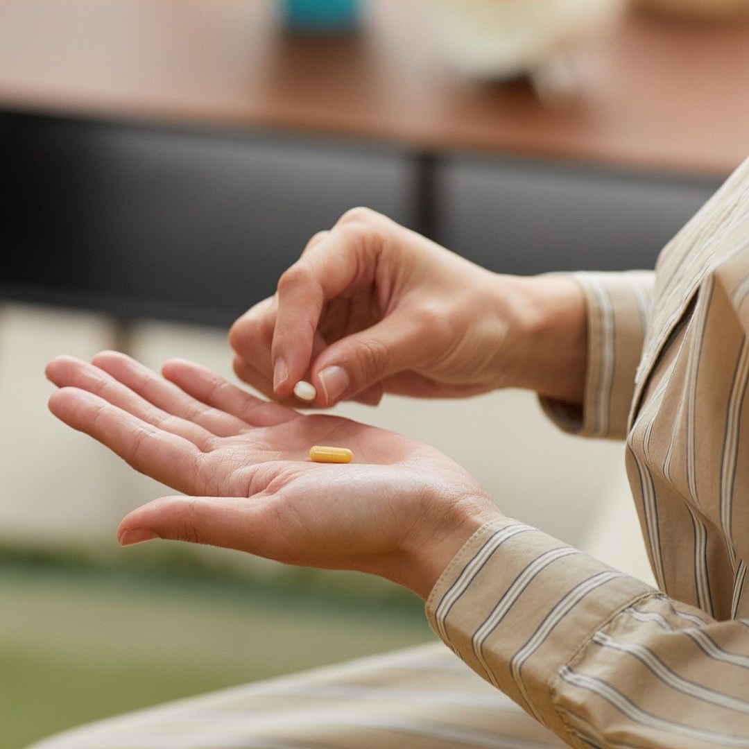 Person preparing to take a yellow capsule.