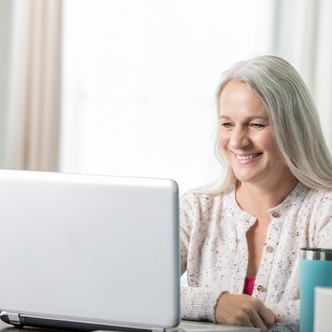 Smiling woman using laptop at home.