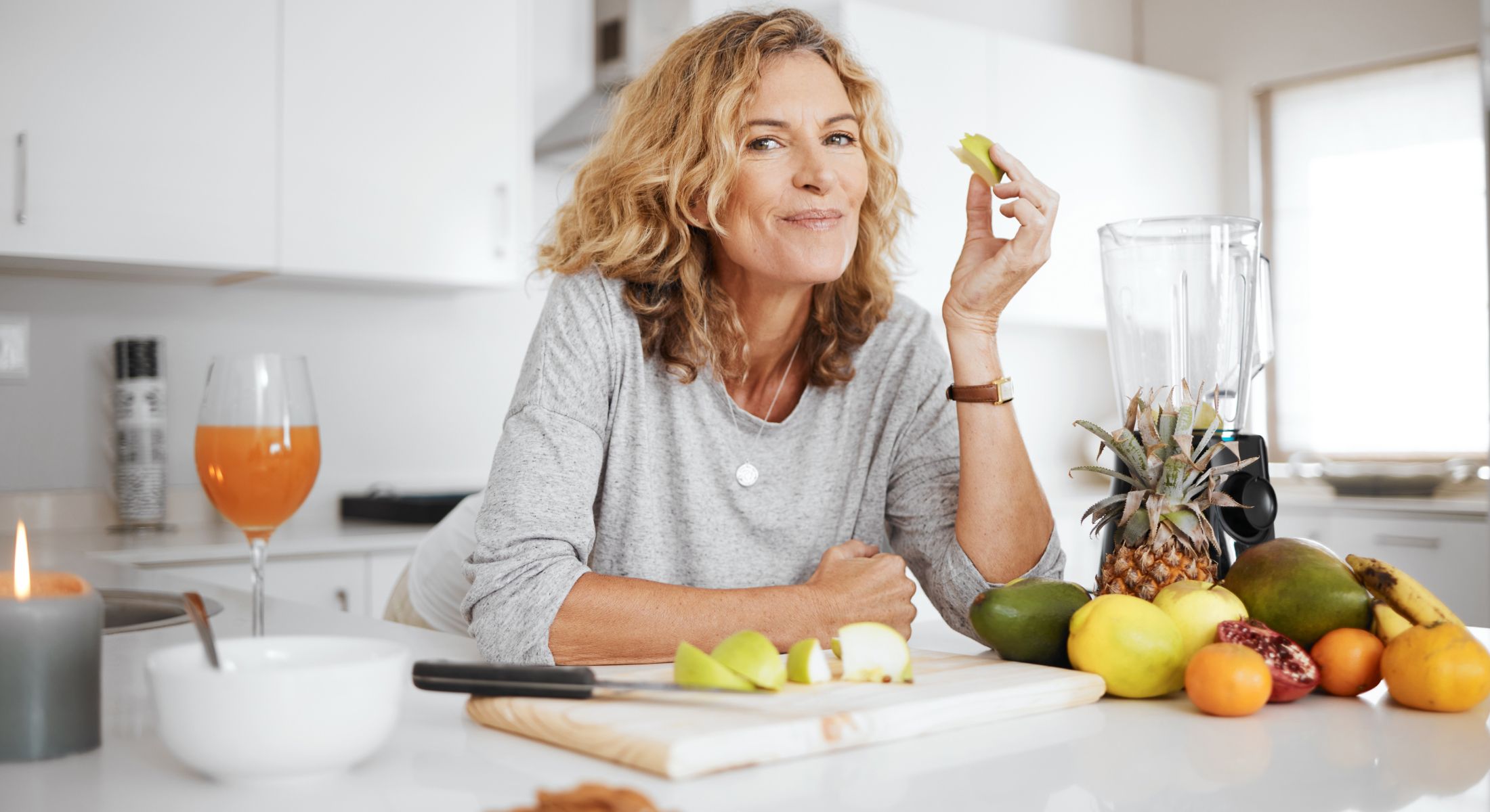 Woman enjoying fresh fruit in bright kitchen.