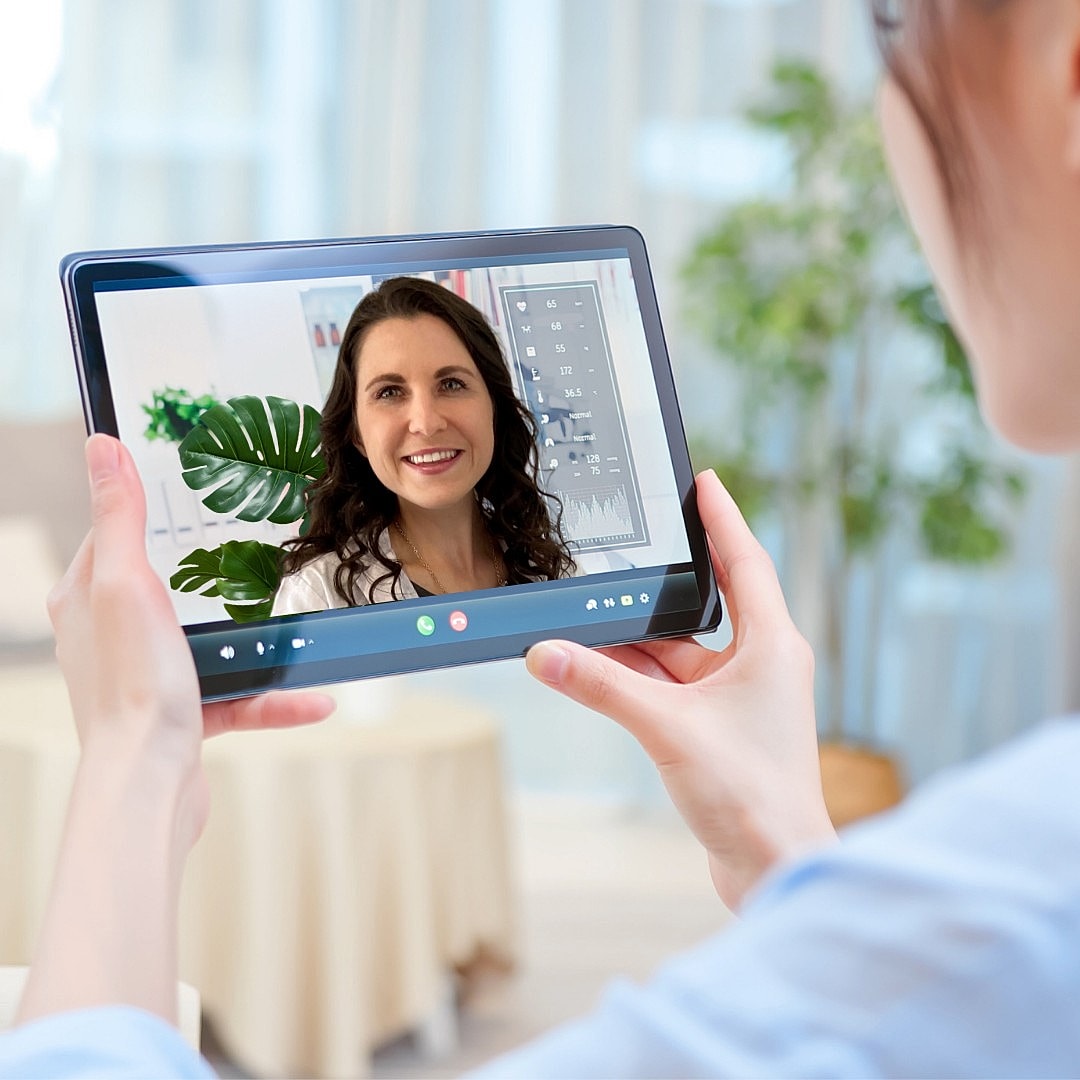 Person video chatting on tablet in bright room.